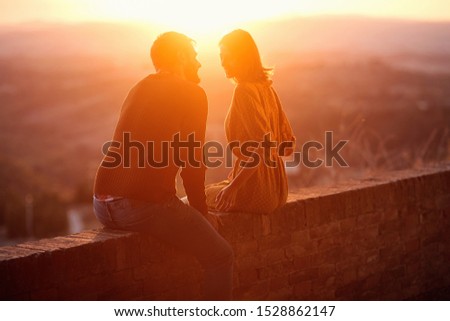 Smiling young man and woman hugging and kissing at sunset