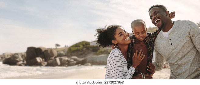 Smiling young man and woman with their son on the beach. Beautiful family on vacation at beach. - Powered by Shutterstock