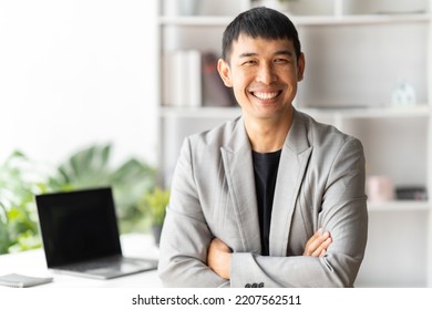 Smiling Young Middle Eastern Businessman Sitting At Worktable At Modern Office