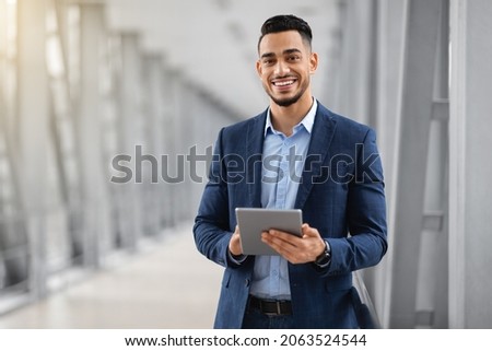 Smiling Young Middle Eastern Man With Digital Tablet In Hands Posing At Airport Terminal, Successful Millennial Arab Businessman Using Tab Computer While Waiting For Flight Boarding, Copy Space Stock foto © 