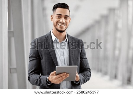 Smiling Young Middle Eastern Man With Digital Tablet In Hands Posing At Airport Terminal, Successful Millennial Arab Businessman Using Tab Computer While Waiting For Flight Boarding, Copy Space