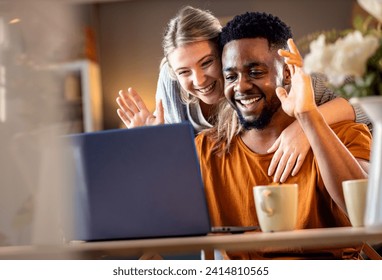 Smiling young mixed couple using a laptop for video call at home. - Powered by Shutterstock