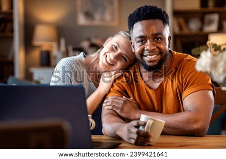 Smiling young mixed couple using a laptop while working on their home finances.