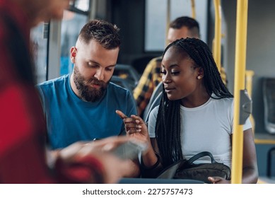 Smiling young multiracial friends talking together in city bus and using a smartphone. Diverse couple laughing and having a conversation while sitting in modern city vehicle. Diversity portrait. - Powered by Shutterstock