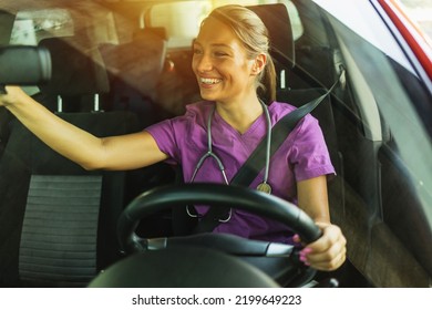 Smiling Young Nurse Driving To Work. A Female Doctor In A Uniform With A Stethoscope Drives Her Car To Work.