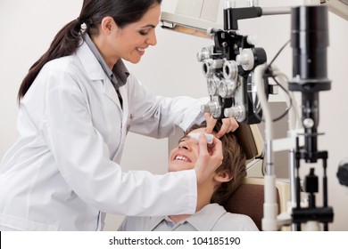 Smiling young optometrist putting eye drops in eyes of patient for clear vision - Powered by Shutterstock