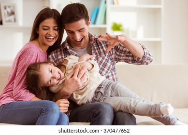 Smiling young parents and their child are very happy, they are at home
