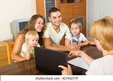 Smiling young parents and two daughters sitting in front of social worker