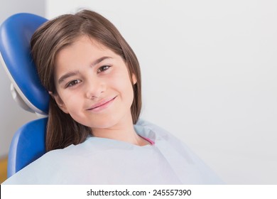Smiling young patient sitting in dentists chair in dental clinic