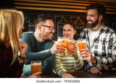 Smiling Young People Drinking Craft Beer In Pub