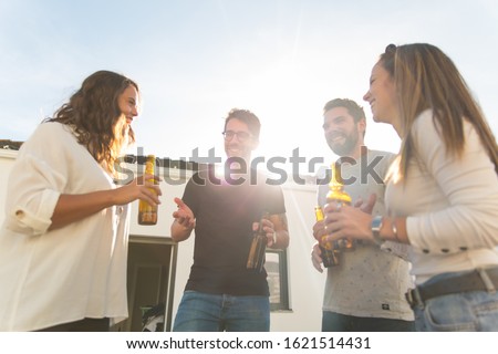 Smiling young people hanging out with beer. Cheerful friends holding beer bottles and laughing. Leisure, friendship concept