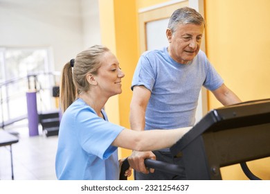 Smiling young physiotherapist assisting elderly man to exercise on treadmill at rehabilitation center - Powered by Shutterstock