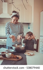 smiling young pregnant mother with dreadlocks is preparing in the kitchen with her son Toddler, make the dough for baking bread, lifestyle, toning, real interior