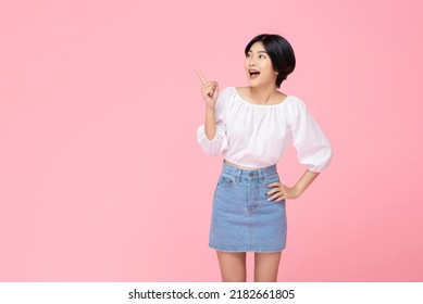 Smiling young pretty Asian woman pointing hand up and looking sideways in pink studio isolated background - Shutterstock ID 2182661805