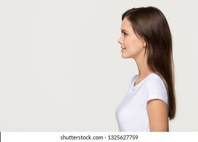 Smiling Young Pretty Woman Standing In Profile Looking Forward At Copy Space, Confident Ambitious Teen Girl Thinking Of Leadership Future Goals Isolated On White Grey Background, Side View Portrait