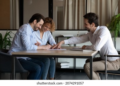 Smiling young professional lawyer financial advisor realtor showing place for signature on paper contract to happy millennial couple clients, satisfied with high quality service making deal agreement.