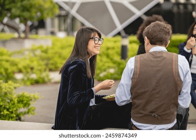 Smiling young professionals enjoying a lively conversation over lunch in an urban park. - Powered by Shutterstock