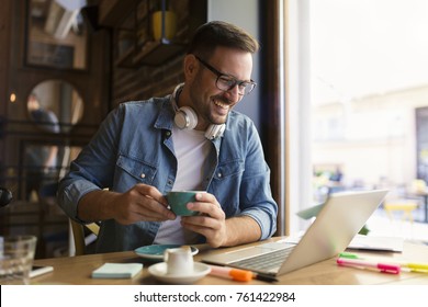 Smiling young student learning on line at coffee house - Shutterstock ID 761422984