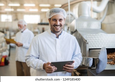 Smiling Young Technologist Using Tablet. Food Factory Interior.