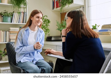 Smiling young teenage female patient talking to professional mental therapist - Powered by Shutterstock