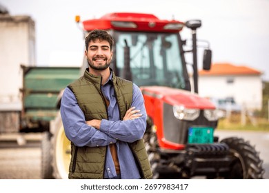 Smiling young tractor driver posing in front of his tractor, symbolizing agriculture, farming, machinery, and rural work.