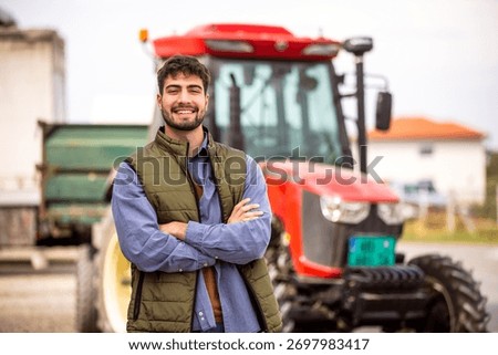 Smiling young tractor driver posing in front of his tractor, symbolizing agriculture, farming, machinery, and rural work.