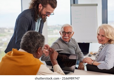 A Smiling Young Tutor Is Explaining To A Small Group Of Senior Students Digital Marketing In A Classroom.