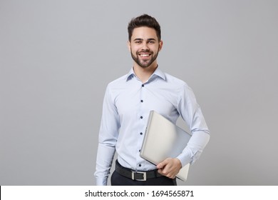 Smiling Young Unshaven Business Man In Light Shirt Posing Isolated On Grey Wall Background Studio Portrait. Achievement Career Wealth Business Concept. Mock Up Copy Space. Hold Laptop Pc Computer