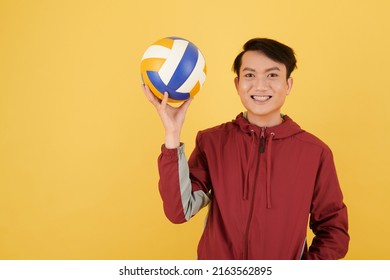 Smiling young Vietnamese man holding volleyball ball, isolated on yellow - Powered by Shutterstock