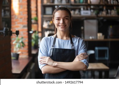 Smiling Young Waitress Or Small Cafe Business Owner Entrepreneur Looking At Camera, Confident Millennial Businesswoman Wear Apron Posing In Restaurant Coffeeshop Interior, Cafeteria Worker Portrait