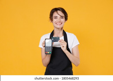 Smiling Young Woman 20s Barista Bartender Barman Employee In Apron Hold Modern Bank Payment Terminal To Process And Acquire Credit Card Payments Isolated On Yellow Background Studio Portrait