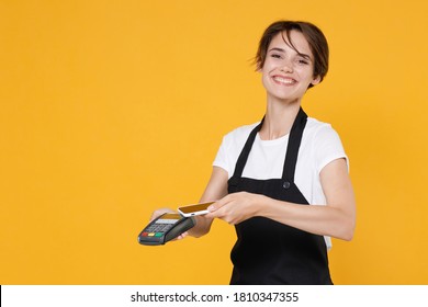 Smiling Young Woman 20s Barista Bartender Barman Employee In Apron Hold Bank Payment Terminal To Process Acquire Credit Card Payments Mobile Phone Isolated On Yellow Background Studio Portrait