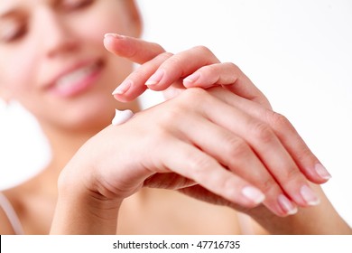 Smiling young woman applies cream on her hands. On a white background.