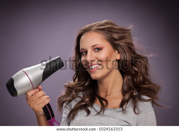 Smiling Young Woman Blow Drying Her Royalty Free Stock Image