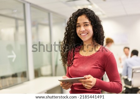 Smiling young woman as a business trainee or student using tablet computer in office