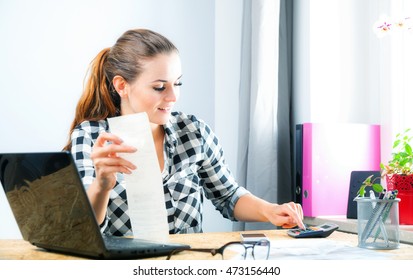 Smiling Young Woman Calculating And Paying Bills In Home Office