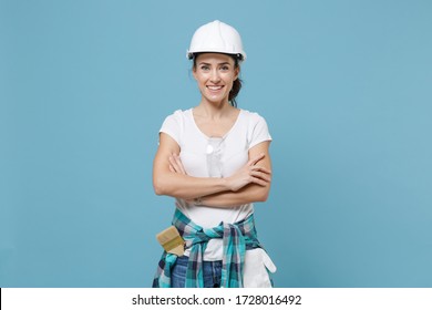 Smiling Young Woman In Casual Clothes Protective Helmet Hardhat Isolated On Blue Background Studio. Instruments Accessories For Renovation Apartment Room. Repair Home Concept. Holding Hands Crossed