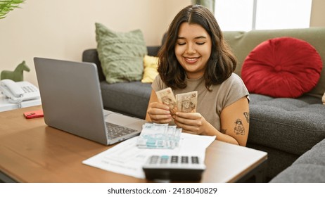 Smiling young woman counting brazilian currency at home with laptop and calculator on desk. - Powered by Shutterstock