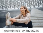 Smiling young woman doing morning gymnastics outdoors. Active life, sports training, healthy lifestyle