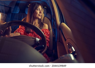 Smiling Young Woman Driving Car At Night