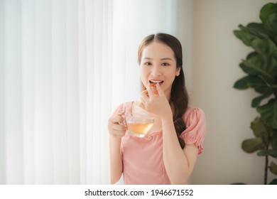 Smiling Young Woman Eating The Pill