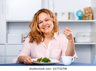 Smiling young woman eating vegetarian salad for weight loss and health