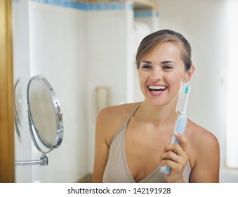 Smiling Young Woman With Electric Toothbrush