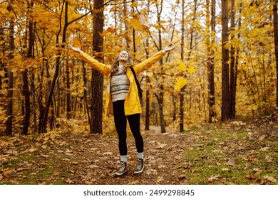 Smiling young woman enjoys the autumn weather in the forest. Autumn landscape. - Powered by Shutterstock