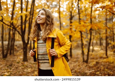 Smiling young woman enjoys the autumn weather in the forest. Autumn landscape. - Powered by Shutterstock