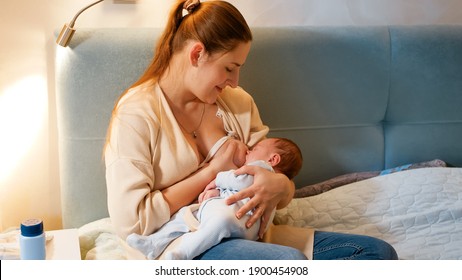 Smiling Young Woman Got Awake At Night Feeding Her Newborn Baby With Breast Milk. Concept Of Healthy And Natural Baby Nutrition. Health Of Mother And Child.