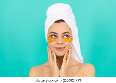 smiling young woman has collagen gold eye patches on face with towel