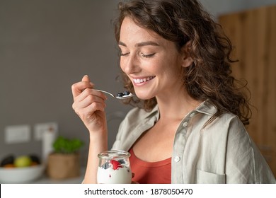 Smiling Young Woman Having Healthy Breakfast At Home With Fruit And Yogurt. Happy Natural Girl Holding Teaspoon With Yogurt And Blueberries. Beautiful Woman Eating Fresh Yoghurt With Berries At Home.