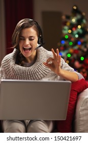 Smiling Young Woman Having Video Chat With Family In Front Of Christmas Tree