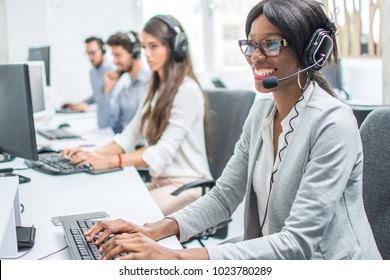 Smiling young woman with headset working in call center.